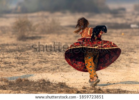 cute little shepherdess with cute 
 new born goat in fields,
nomadic life of shepherds traveling with sheep in the the dust
