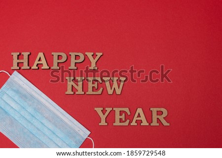 Medical protective mask on red background. Inscription Happy New Year. Christmas and New Year card, banner, advertising concept. Top view photo, minimalism, copy space. Medical flatly.