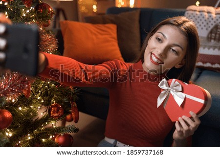 Happy woman taking a selfie with a Christmas gift at home, social media and holidays concept