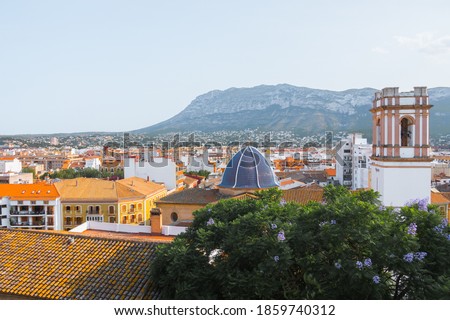 Beautiful aerial cityscape of Denia, the Church of the Assumption and mountains. Shot from the historic moorish castle in the old town that holds the Palau del Governador. Valencian Community, Spain.