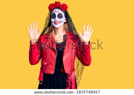 Woman wearing day of the dead costume over background showing and pointing up with fingers number ten while smiling confident and happy. 