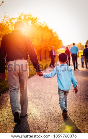 father and son walking in the sunset, holding hands