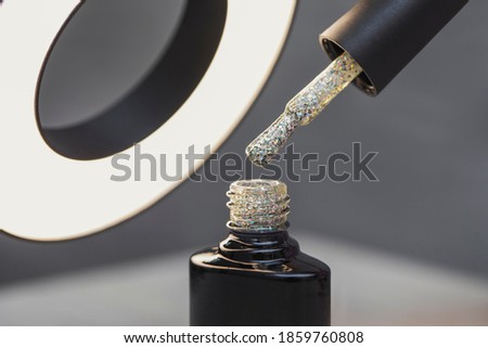 A bottle with a bright beautiful glitter varnish in a beauty salon. Varnish for New Year's nail design. Macro photo of objects.