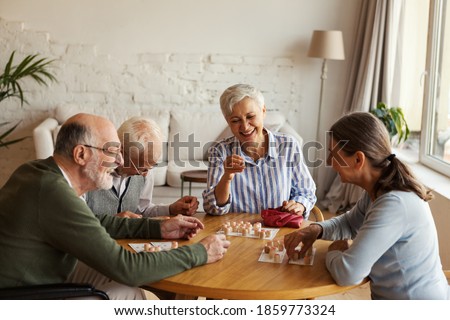 Group of four cheerful senior people, two men and two women, having fun sitting at table and playing bingo game in nursing home Royalty-Free Stock Photo #1859773324