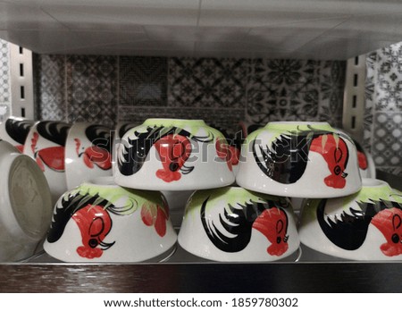 Red chicken branded ceramic cups sold in the market.