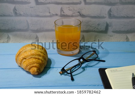 Still life with notepad, glass of juice and pen on the wooden background