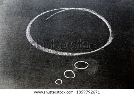 White color chalk hand drawing in round thinking bubble speech shape with blank space on black board background