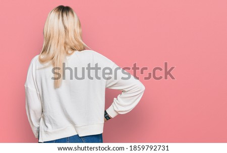 Young caucasian woman wearing casual winter sweater standing backwards looking away with arms on body 