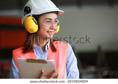 Portrait beautiful asia engineer wearing PPE safety helmet , safety glasses , 
Safety vest and earmuff work in factory Royalty-Free Stock Photo #1859804809