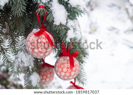 Christmas red baubles hanging on spruce branch with snow outdoors