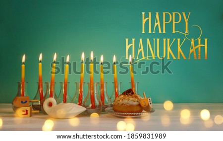 Image of jewish holiday Hanukkah with creative menorah (traditional Candelabra), donut and wooden dreidel (spinning top)