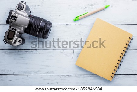 Recycle notebook and old camera on blue wooden background