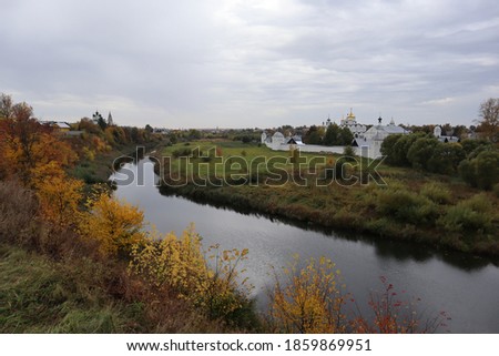 Autumn landscape, top view of the river, yellow trees, churches, hill and houses.