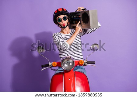 Portrait photo of girl in helmet motorbike pressing on button listening music boombox whistling sign isolated on vivid purple background