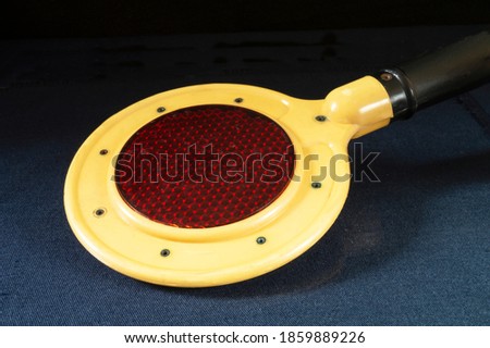  Traffic controller with red glass on black background. Yellow subject with black handle close-up