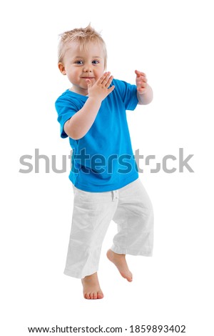 CUTE LITTLE BOY STANDING ON ONE LEG WHILE CLAPPING HANDS ISOLATED ON WHITE BACKGROUND