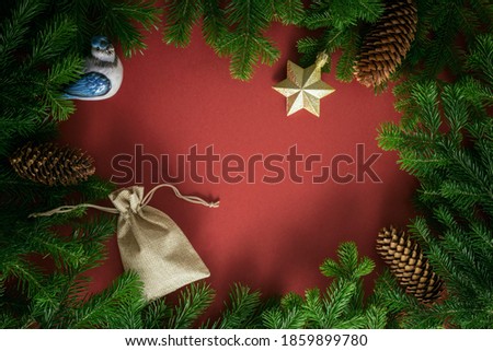 Christmas card. Composition from Christmas decorations, postcard and branches of fir on a red background. Flat lay, top view, copy space.