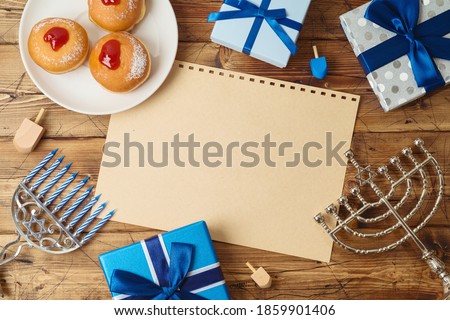 Jewish holiday Hanukkah background with traditional donuts, menorah and gift box