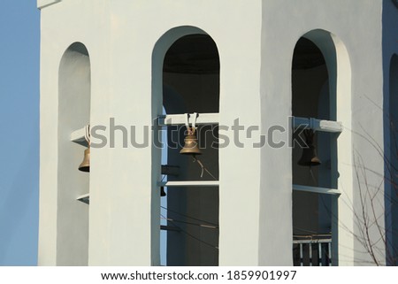 Belfry with copper bells on the bell tower of the Orthodox Church. Metal bells hang in the vaults of the bell tower of an Orthodox church in Russia against the blue sky.