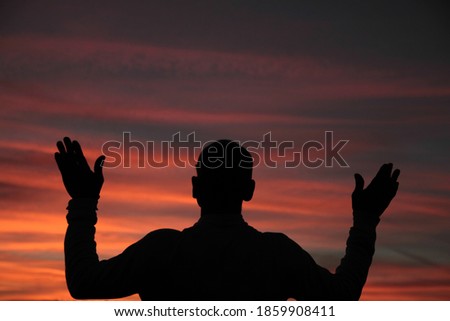 praying to god with arms outstretched in the sky sunset stock photo