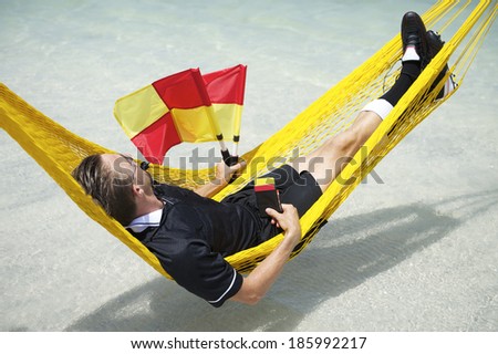 Soccer football referee taking a break from the match to relax at the beach in hammock