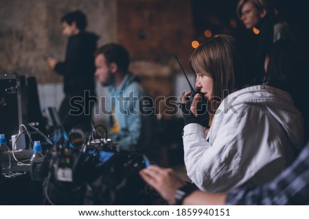Director at work on the set. The director works with a group or with a playback while filming a movie, advertising, or a TV series. Shooting shift, equipment and group. Modern photography technique. Royalty-Free Stock Photo #1859940151