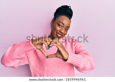 Young african american woman wearing casual winter sweater smiling in love doing heart symbol shape with hands. romantic concept. 