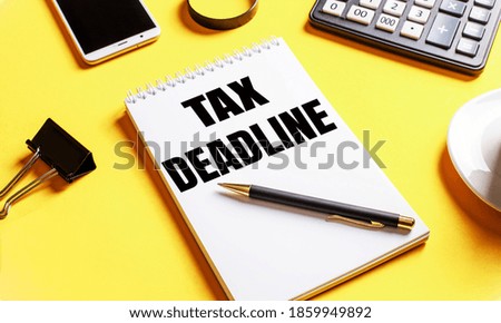 On a yellow background, a notebook with the text TAX DEADLINE, coffee, calculator, telephone and a clip for papers. Business concept