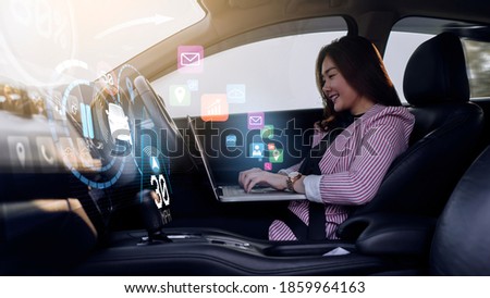 Auto pilot self driving car businesswoman working using computer laptop, HUD Head Up Display and digital instruments panel autonomous user interface navigation utility screen smart technology hologram