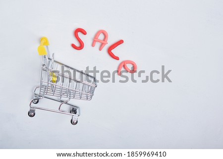 inscription sale and shopping trolley on gray background