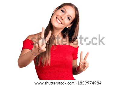 Young beautiful hispanic woman wearing casual clothes smiling looking to the camera showing fingers doing victory sign. number two. 
