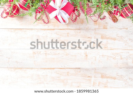 Festive Xmas background with fir tree branches, red winter berries, candy cane decoration and festive gift boxes, top view copy space