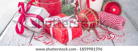 Festive composition with fir tree branches, Christmas decor and baubles, gift box with festive ribbons, Xmas sweets and mugs for hot chocolate, white background copy space