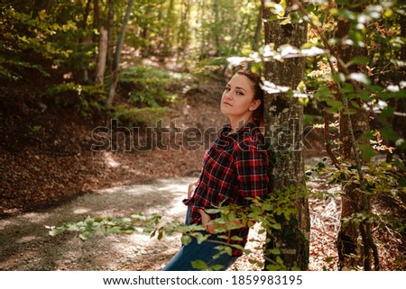 traveler hipster woman standing alone in autumn woods in checkered shirt and blue jeans . Cold weather, fall colors. Wanderlust concept.