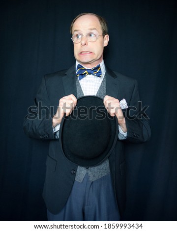 Portrait of Man in Dark Suit Holding Bowler Hat With Fearful Expression. Vintage Fashion. Retro Style. Concept of Anxiety or Apprehension. Stereotypical British Gentleman.