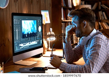 Tired overworked young business man taking off glasses rubbing tired dry eyes after long pc computer work late at dark night, having vision problem, bad sight, feeling eyestrain fatigue pain concept. Royalty-Free Stock Photo #1859997670
