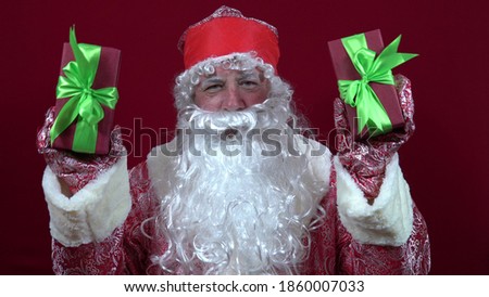 Russian santa claus holds Christmas gifts in both hands and shakes them to give
