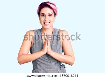 Young beautiful woman with pink hair wearing casual clothes praying with hands together asking for forgiveness smiling confident. 