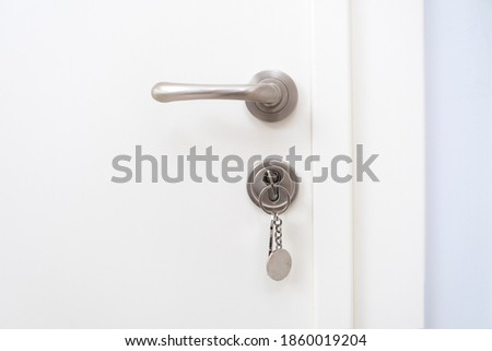 metal door handle and key in the keyhole of the white exterior door of the house Royalty-Free Stock Photo #1860019204