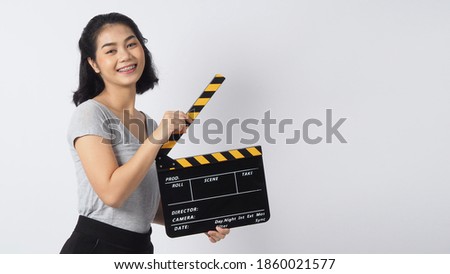 Teenage girl or woman wearing braces and contact lenses.
Her hand's holding black clapper board or movie slate use in video production ,film, cinema industry on white background.