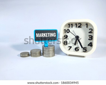 A picture of coin,clock and MARKETING word on blue board.It is for business and finance concept with white background.