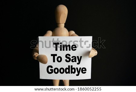 The wooden man holds a white sign with the text TIME TO SAY GOODBYE in his hands. The content of the lettering has implications for business concept and marketing.