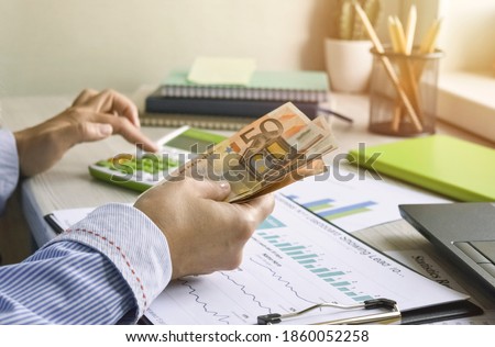 Female hands close up. Business woman, an accountant works at the table, counts money, holds a banknote in her hands. Work desk with laptop and graphs.