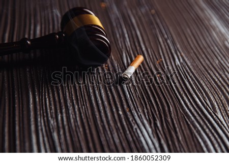 Wooden judge gavel and smoking cigarette on a table. Tobacco law