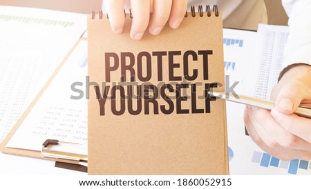 Text PROTECT YOURSELF on brown paper notepad in businessman hands on the table with diagram. Business concept