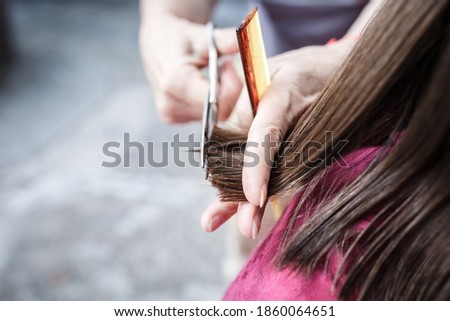 Young girl mean hair with a comb and scissors on a sunny day in the fresh air.