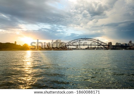 Great view of the famous sightseeing of Opera house in Sydney, Australia. Harbor bridge view from the bay by the ocean at the sunset. 