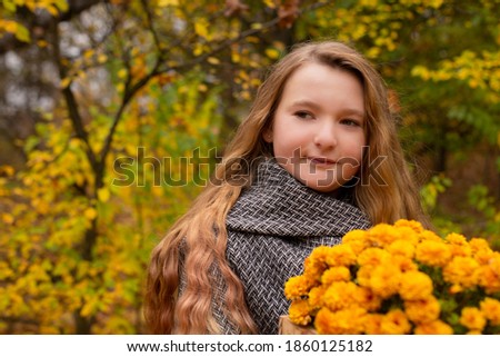 cute brunette teen girl in gray coat holding a wooden basket of flowers. Cosiness, autumn.