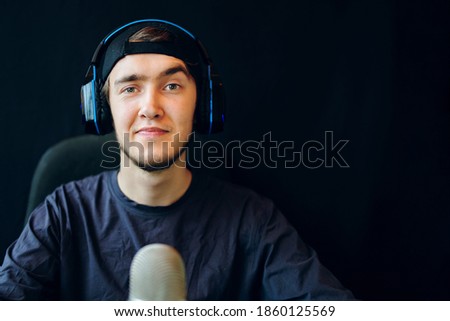 Cyber sport. Handsome game streamer wins a round in a competitive game. Streaming online games on internet. The guy with the headphones is recording the voice.