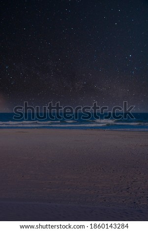 A Wide Open Beach Scene With a Starry Night Sky in the Background